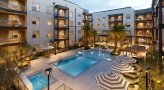 swimming pool in a courtyard with lounge chairs and umbrellas around it
