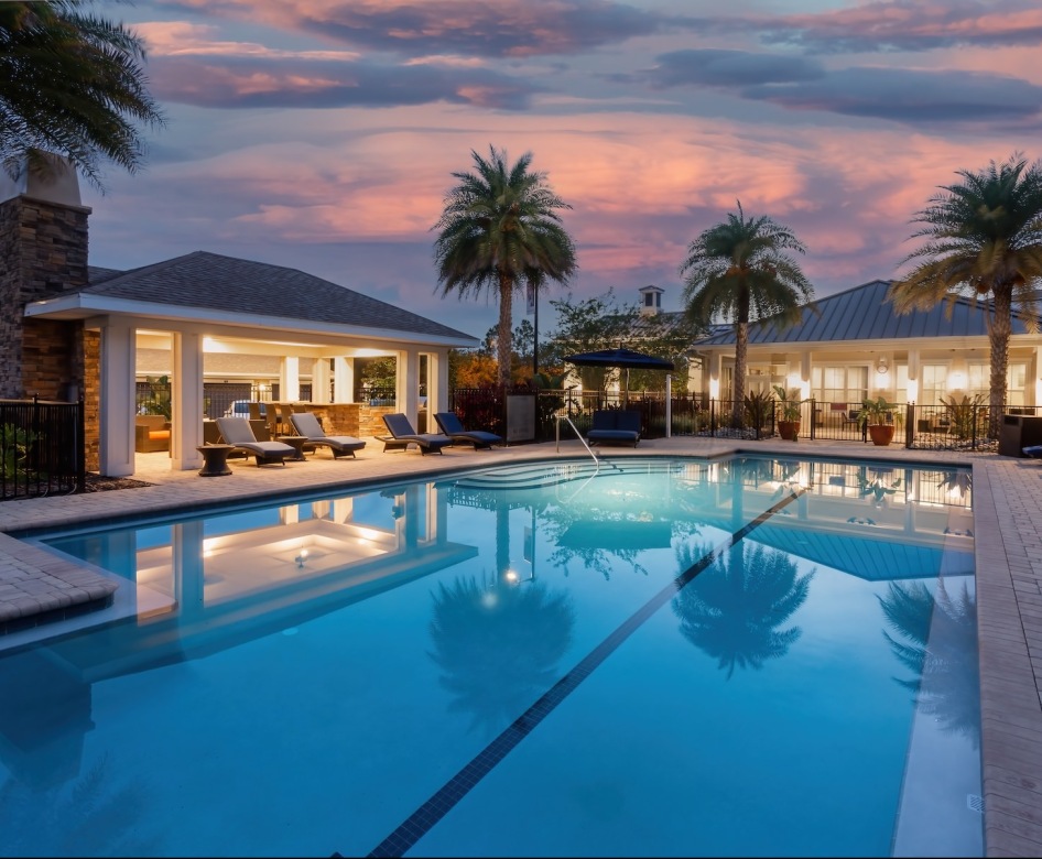 a resort style pool with seating at dusk