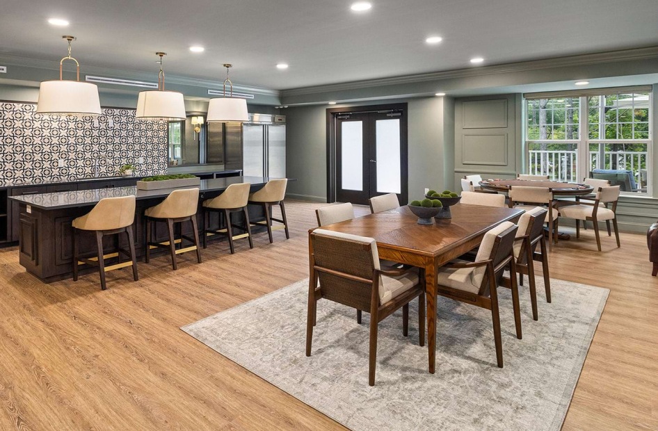 Album Matthews clubhouse lobby with two dining tables and a counter top with bar stools and large bay window.