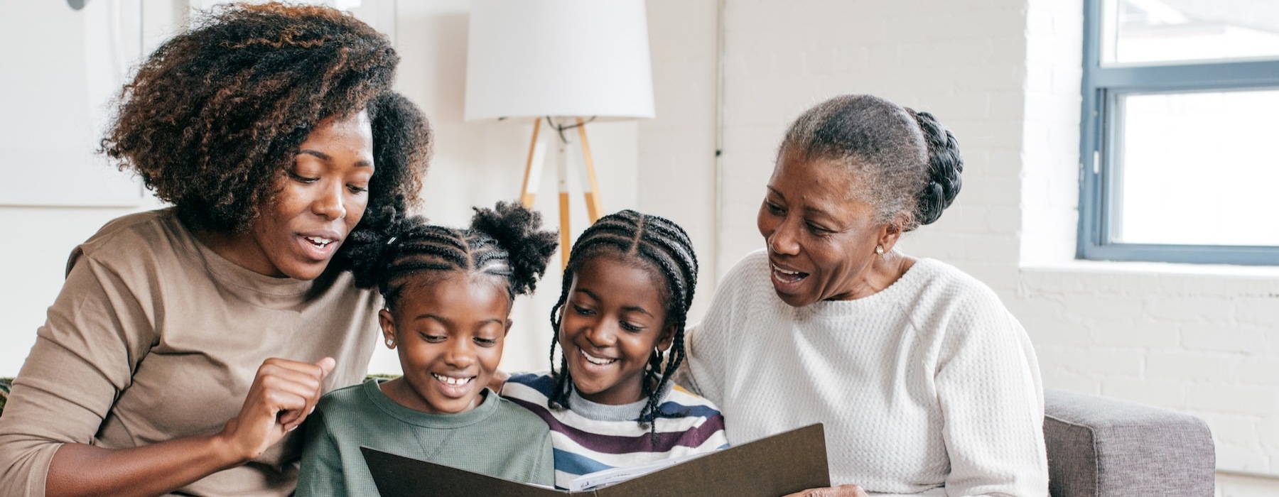 a family sitting on a couch looking at a book