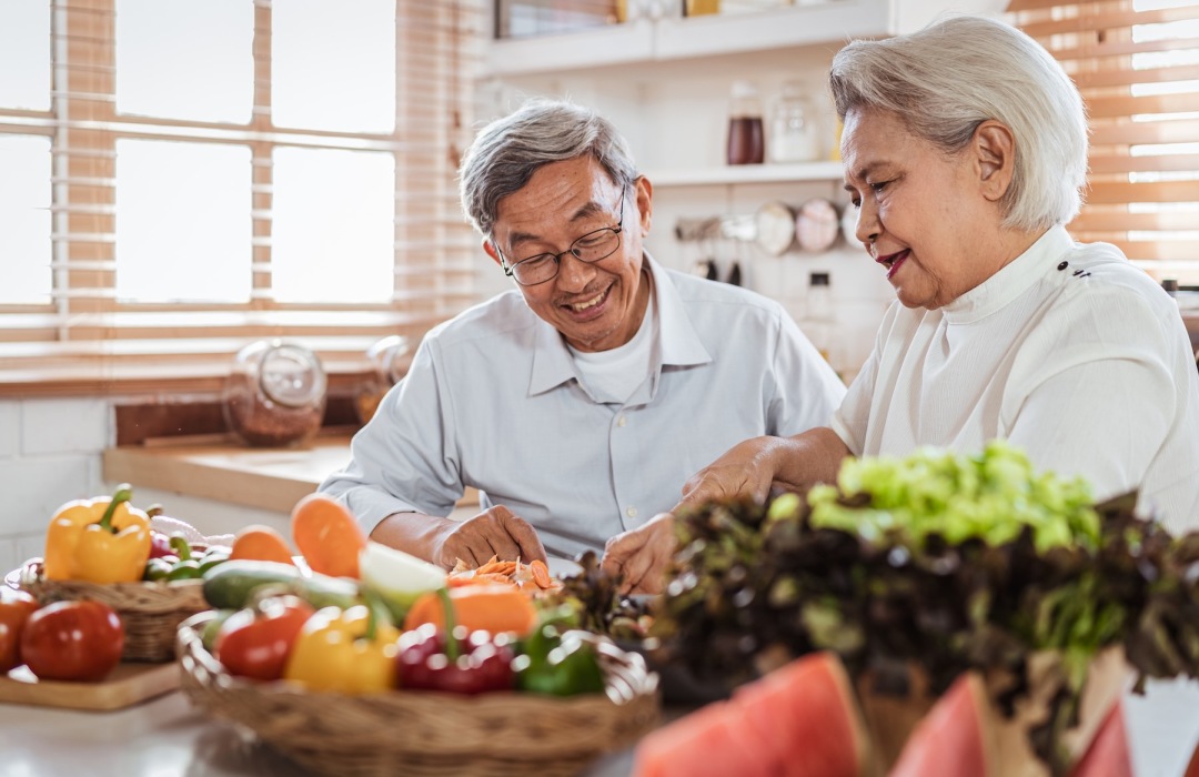 an older couple chopping vegtables