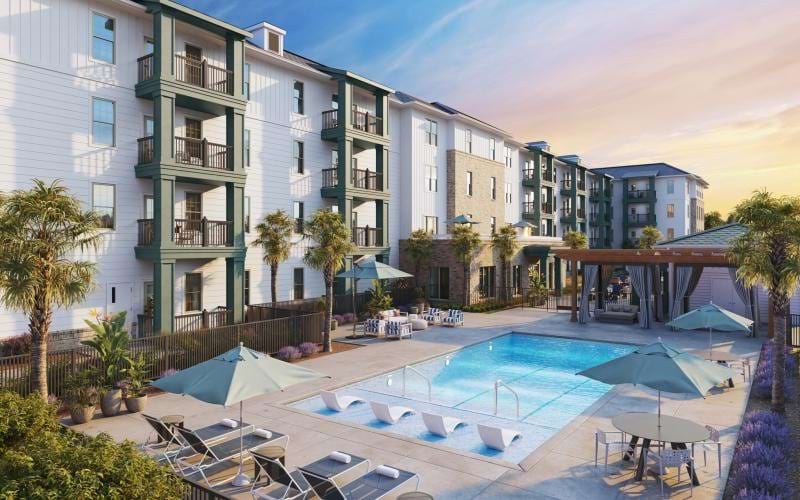 a pool with lounge chairs and umbrellas next to a building