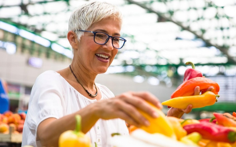 a woman smiling and holding a bunch of vegetables
