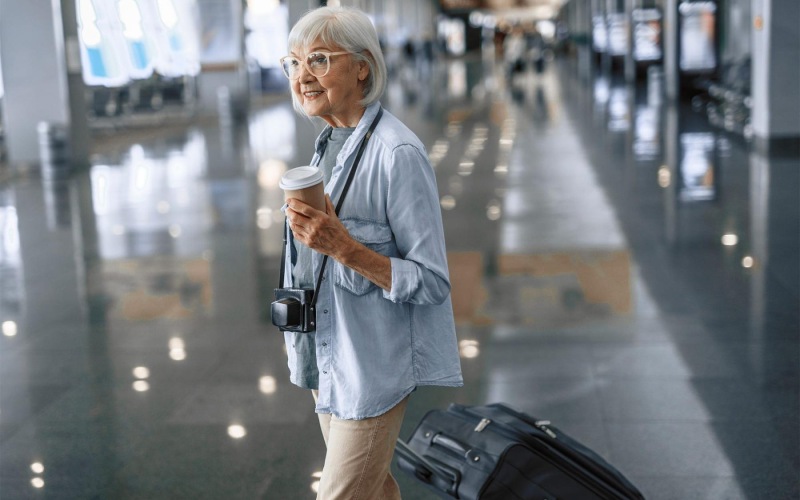 Find your perfect fit at Album Monterey Pointe a woman with a coffee cup and luggage in an airport