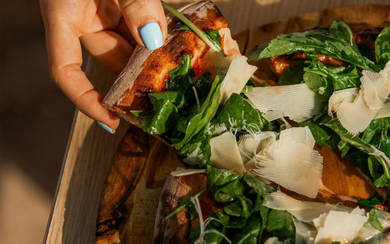 a person holding a slice of pizza